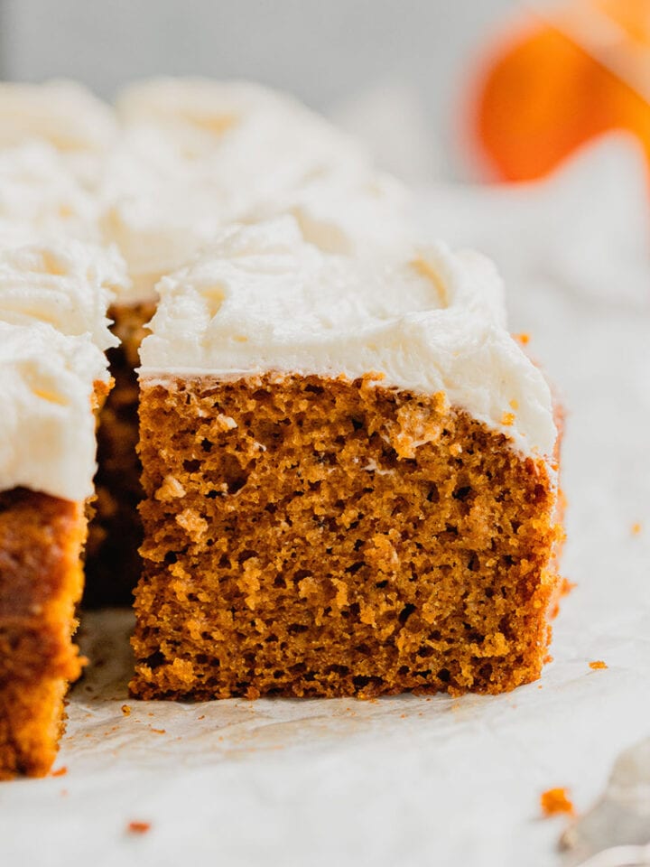 Cream cheese frosted pumpkin bars on a piece of parchment paper.
