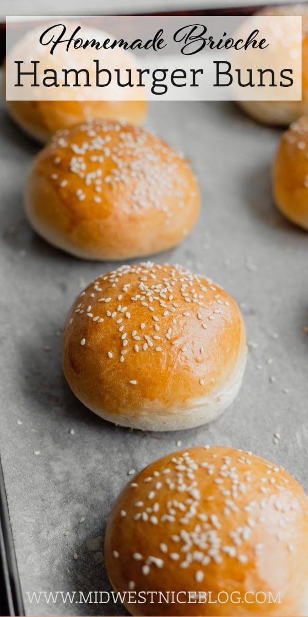 Brioche burger buns are arranged on a parchment lined baking tray.