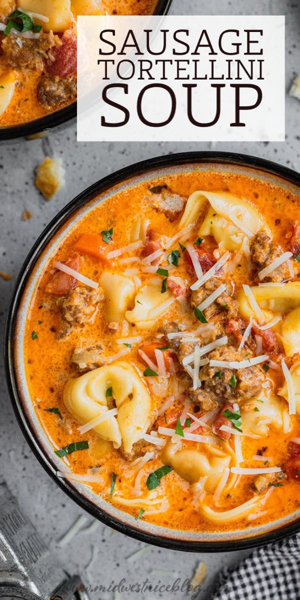 A bowl of sausage and tortellini soup garnished with extra parmesan cheese.