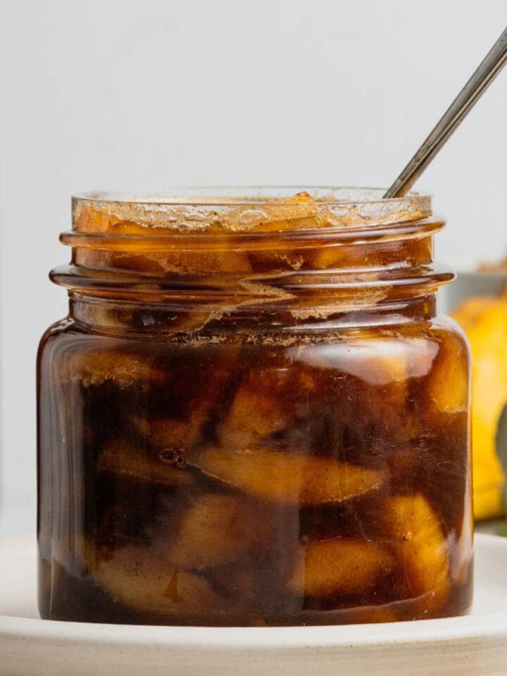 Spiced pear compote in a glass jar with a spoon in it.