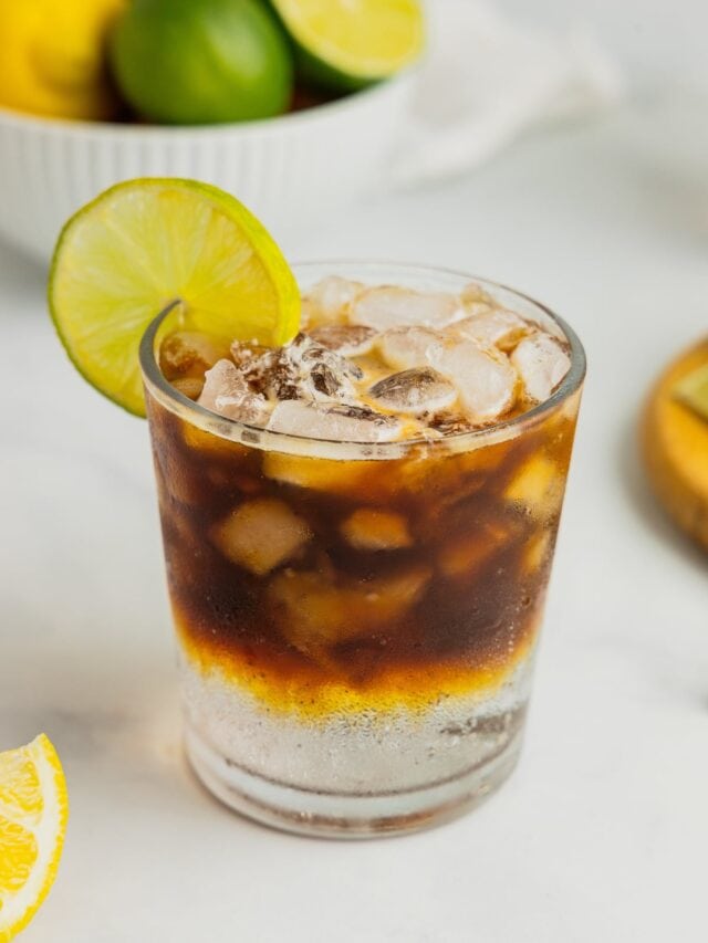 An espresso tonic in a rocks glass garnished with a lime wheel.
