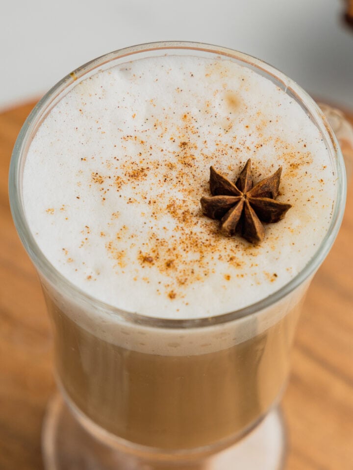 A clear mug filled with a hot vanilla chai latte garnished with chai spice and a star anise.