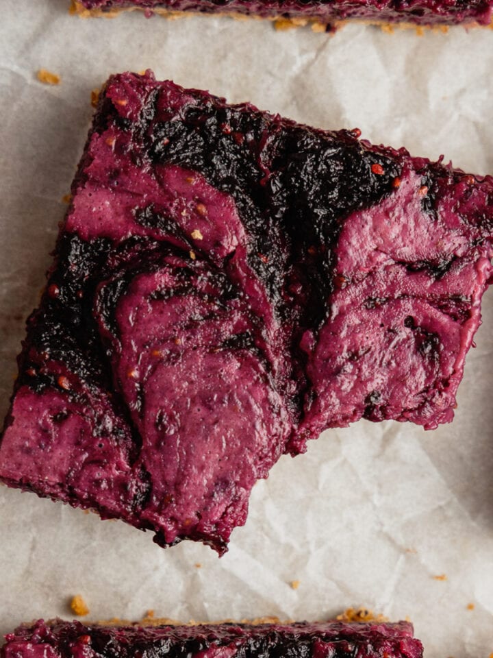 An overhead image of a square piece of mulberry cheese with a bite taken out of it.
