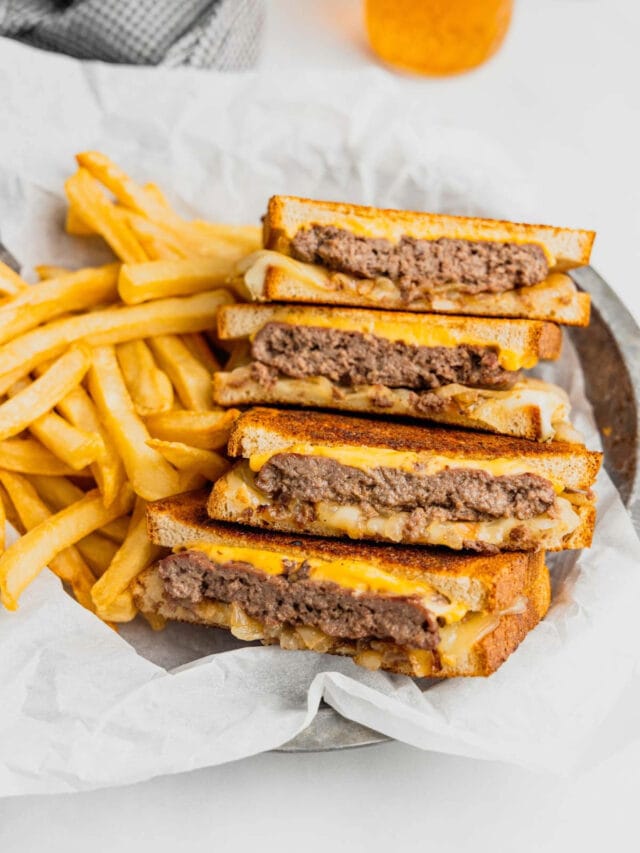 Venison patty melts sit on a tray with french fries.