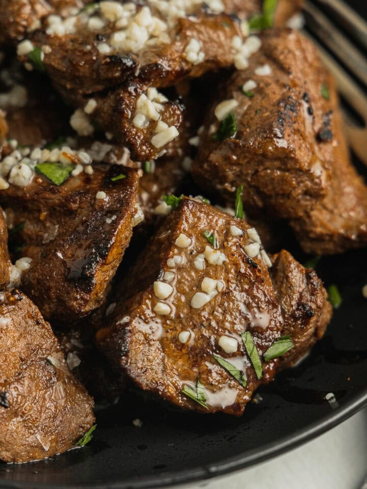Cubes of venison steak that have been cooked in the air fryer are drizzled with melty garlic butter.
