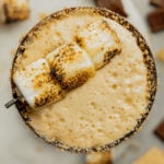 An overhead view of a martini glass filled with a s'mores espresso martini garnished with a toasted marshmallow skewer.