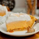 A slice of no bake pumpkin pudding pie with salted caramel and topped with cool whip on a white plate.